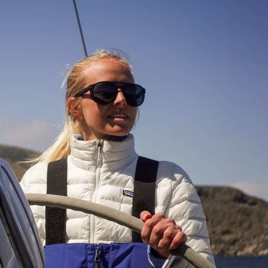 At the helm of a sailboat, wearing basn5 Fort Point